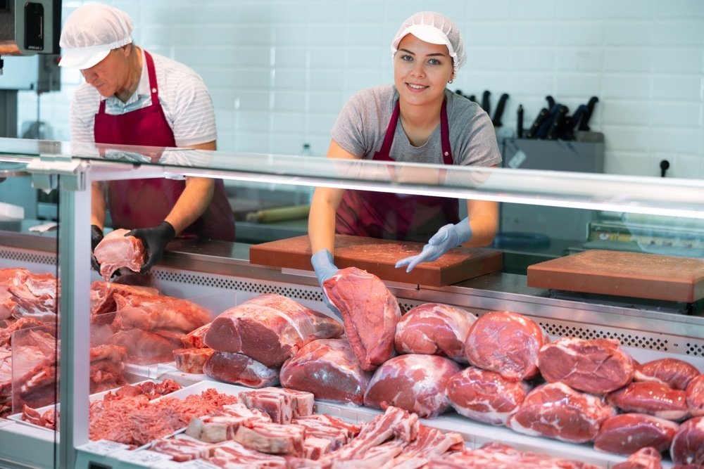 Smiling,Skilled,Young,Female,Butcher,Working,Behind,Counter,In,Butchery,